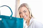 Young woman sitting behind turquoise shopping bag