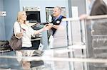 Young woman and salesman looking at ovens in showroom