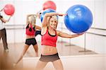 Young woman holding exercise ball in aerobics class