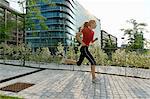 Young woman running past office buildings