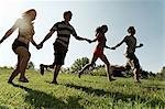 Group of young adults holding hands and running