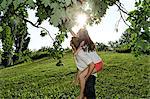 Young couple reaching up to tree branches