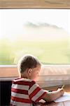 Young boy drawing on train