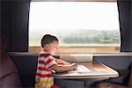 Young boy with pencil and paper on train