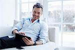 Man relaxing on sofa using digital tablet