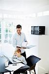 Boy using laptop and man looking at paperwork