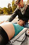 Pregnant woman lying beside river