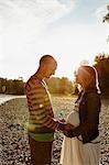 Pregnant woman and partner standing face to face beside river holding windmill