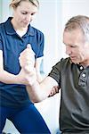 Physiotherapist helping man to do arm exercise