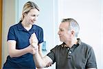 Physiotherapist helping man to do arm exercise