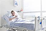 Patient lying on hospital bed using digital tablet