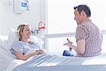 Patient lying in hospital bed talking to visitor