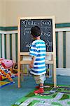 Boy standing beside blackboard with algebra