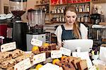 Young woman using cash register in cafe