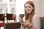 Portrait of young woman drinking coffee in cafe