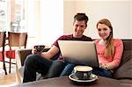 Young couple looking at personal computer in cafe