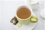 Used Tea Bag on Saucer with Cup of Tea in Green Mug with Sugar Bowl, Studio Shot