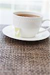 Cup of tea in white porcelain cup with saucer and tea bag, studio shot