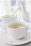 Cup of tea in porcelain white teacup with saucer, sugar bowl, and teapot, studio shot