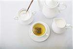 Cup of tea in porcelain white teacup with saucer, sugar bowl, creamer and teapot, studio shot