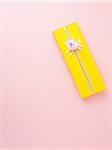 Gift wrapped in yellow wrapping paper on pink background, studio shot