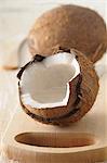 A whole coconut and one broken open, on a wooden board