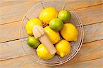 Lemons and limes in a wire basket with a lemon squeezer