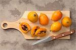 Medlars, whole and halved, on a chopping board