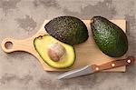 Fresh avocados on a chopping board with a knife