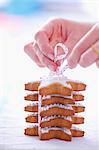 Woman tiding a pile of gingerbread stars garnished with icing