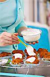 A woman spreading glacÈ icing on carrot muffins