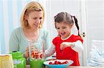 A mother and daughter preparing a strawberry milkshake