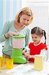 A mother and daughter preparing a strawberry milkshake