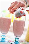 A scoop of strawberry ice cream being added to a milkshake