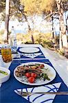 Grilled lamb chops with green asparagus, cherry tomatoes and roast potatoes on a table outdoors