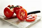 Sliced tomatoes and whole tomatoes on a board with a knife