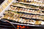 Courgette strips in an aluminium tray on a barbecue