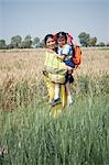 Woman carrying her schoolgirl in the field, Sohna, Haryana, India