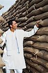 Man looking at stacks of wheat sacks in a warehouse, Anaj Mandi, Sohna, Gurgaon, Haryana, India