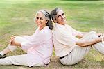 Mature couple sitting back to back on grass in a park, Lodi Gardens, New Delhi, India