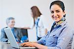 Portrait of a businesswoman working on a laptop with her colleagues in the background