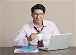 Businessman sitting in front a laptop having coffee