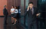 Businessman talking on a mobile phone with their colleagues in the background