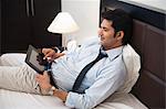 Businessman using a digital tablet on the bed