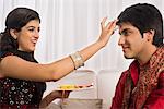 Teenage girl applying tilak to her brother at Raksha Bandhan