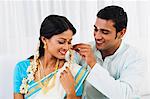 South Indian man putting gajra in his wifes hair
