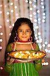 Girl holding a plate of oil lamps on Diwali