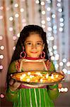 Girl holding a plate of oil lamps on Diwali