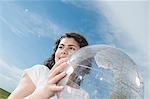 Girl holding transparent globe outdoors