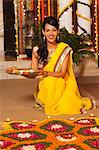 Woman decorating rangoli with oil lamps on Diwali